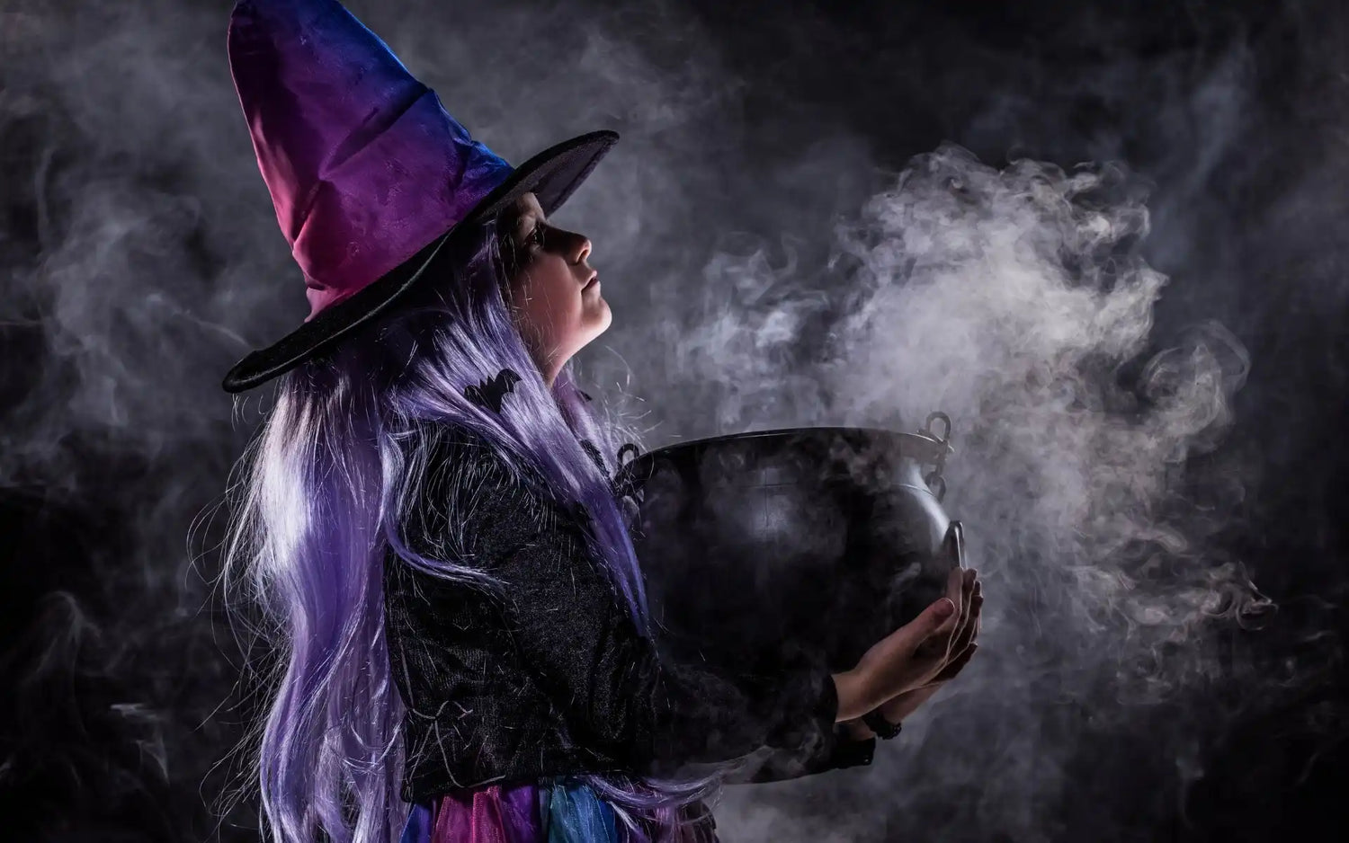 Wiedźma w ostrej czapce i fioletowym warkoczu, trzymająca parujący kocioł.